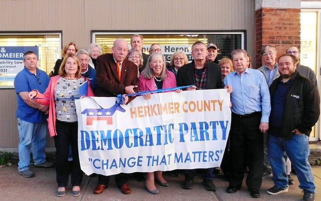 The Herkimer County Democratic Committee held a ribbon-cutting for its new headquarters at 525 Albany St., Little Falls, Wednesday. “We’re delighted to be in Little Falls, which is a vibrant, exciting community,” said Arlene Feldmeier, committee chairwoman, before the ribbon-cutting. Feldmeier said the committee used to meet at Frank J. Basloe Library in Herkimer. The new location, however, gives them “a place of our own,” she said. The space has a meeting room for the committee to conduct business. The committee meets the third Tuesday of the month. Of the committee members included in the pictured are Feldmeier, center, holding the banner, with Little Falls Common Council President Mark Ruffing, on left, and Little Falls Fourth Ward Alderman Dan Carter on right. [STEPHANIE SORRELL-WHITE/TIMES TELEGRAM]