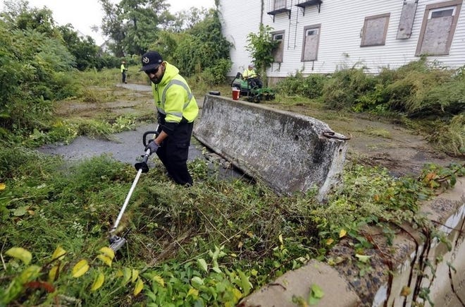 Joao Silva and fellow New Bedford DPI workers clear out an abandoned property at Bonneau Court in September 2018. [Peter Pereira | The Standard-Times File]