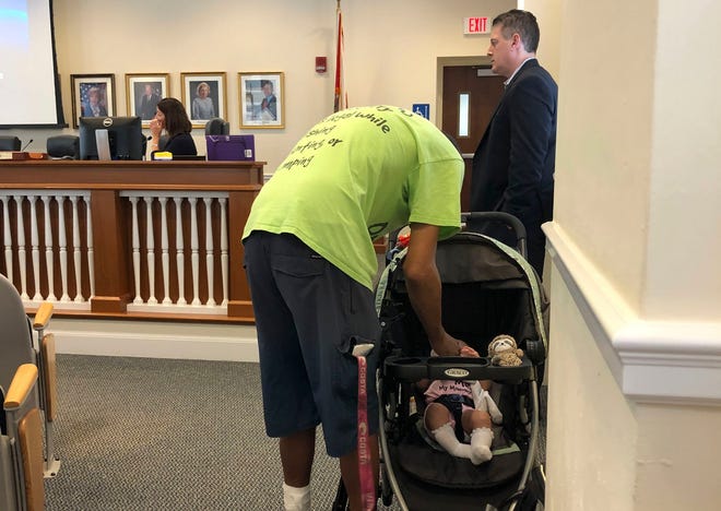 Florida Carry member Michael Taylor tends to his baby after his three-minute public comment at Thursday’s Ordinances, Rules and Standards Committee meeting. Town Manager Kirk Blouin stands beside him. [ADRIANA DELGADO/palmbeachdailynews.com]