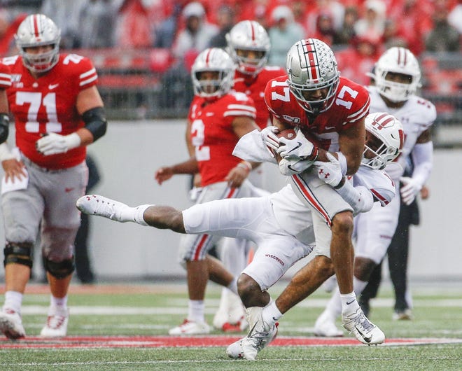 Ohio State receiver Chris Olave fights for extra yardage as Wisconsin cornerback Faion Hicks tries to bring him down after a third-quarter reception. Olave caught seven passes for 93 yards and two touchdowns Saturday. [Joshua A. Bickel/Dispatch]