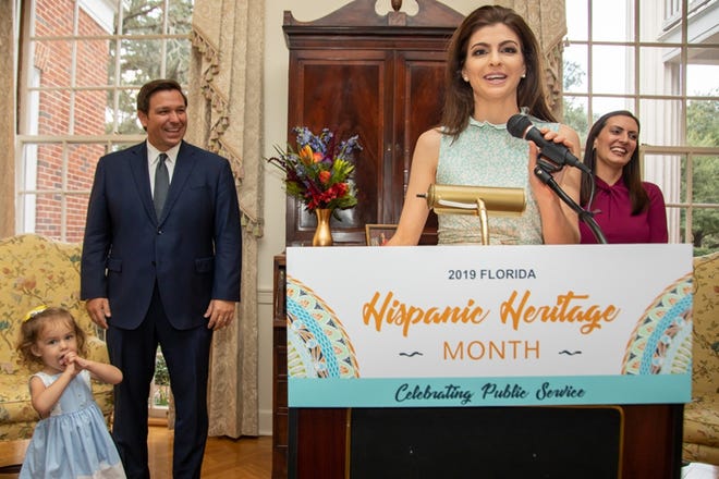 Florida's first lady, Casey DeSantis, announces winners at the awards ceremony for Hispanic Heritage Month with Gov. Ron DeSantis in the background. [Provided by Governor's Office]