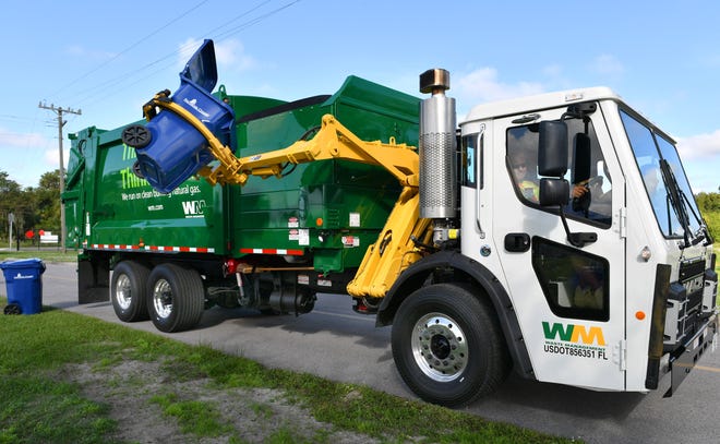 Waste Management route driver Willie Torres demonstrates how new trucks will use a hydraulic arm for curbside pick-up of the new recycling carts in unincorporated parts of Sarasota County. [Herald-Tribune staff photo / Mike Lang]