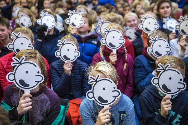 Children hold up masks of the face of fictional character Greg Heffley during a gathering with author Jeff Kinney, at the publishing house Gyldendal in Oslo, Norway, in 2018. [Ole Berg-Rusten/NTB scanpix via AP]