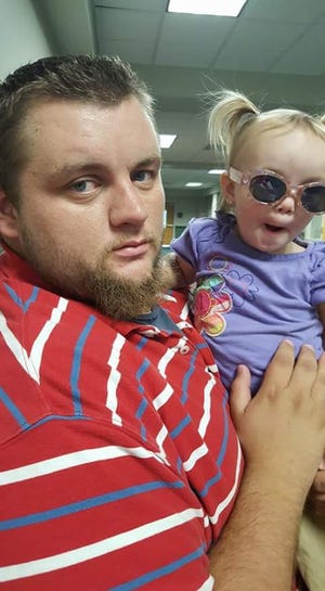Trenton Beasley holds Sophia Beasley in this 2015 family photo. Trenton Beasley died in October of that year. Last week his daughter honored him by purchasing 150 barbecue plates at a W.A. Bess Elementary School fundraiser. She gave those lunches away to those who helped her and her mom during Trenton Beasley’s illness and after his death. [SPECIAL TO THE GAZETTE]
