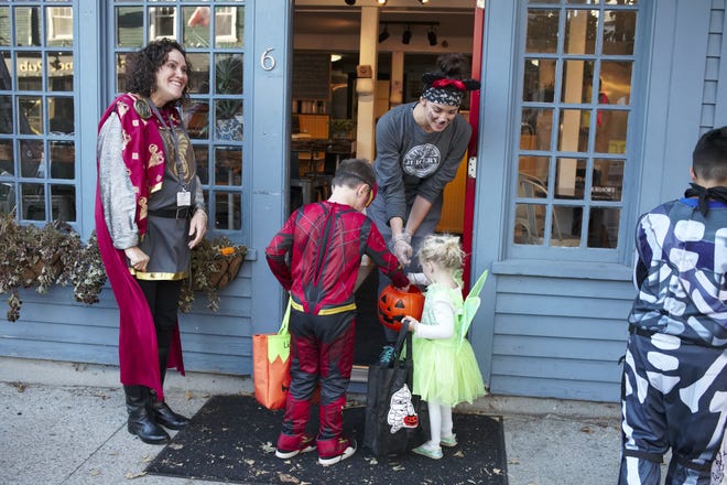 Amanda from Raw Bob's Organic Juicery on Broadway hands out candy to trick-or-treaters while Diana Wood from the East Bay Community Action Program leads the Broadway Halloween Stroll in 2018.[PETER SILVIA PHOTO]