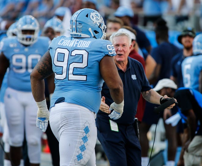 North Carolina head coach Mack Brown, right, greets defensive lineman Aaron Crawford after Crawford sacked South Carolina Gamecocks quarterback Jake Bentley in the second half of the season opener on August 31 in Charlotte. [AP File Photo/Nell Redmond]