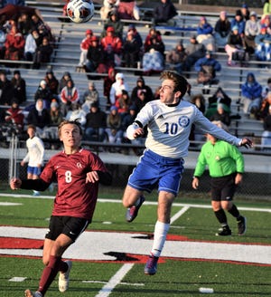 Tyler Masters heads a shot up the field past Columbus Academy defender Campbell Gwin. during action in the Div. II regional championship Saturday in Coshocton.
