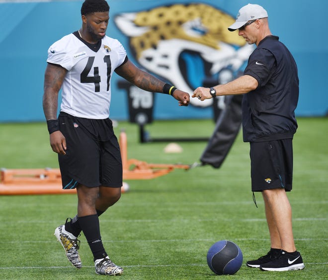 Tom Myslinski (right), the Jaguars' strength and conditioning coordinator, bumps fists with Josh Allen during training camp. [Bob Self/Florida Times-Union]