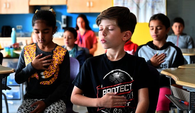 Gio Ferreira, center, and other fourth-graders at the Woodland Elementary School in Milford take part in a recent breathing exercise during class. Teacher Donna Williams has incorporated the breathing and other mindfulness strategies into daily lesson plans. [Daily News and Wicked Local Staff Photo / Ken McGagh]