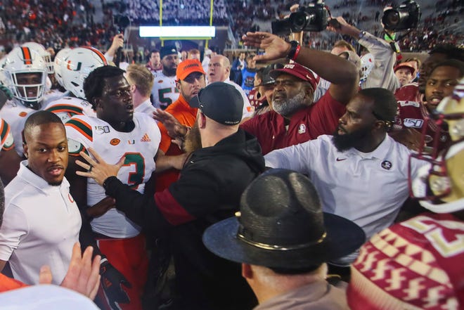 Miami and Florida State players are separated by coaches as they skirmish after an NCAA college football game Saturday, Nov. 2, 2019, in Tallahassee, Fla. Florida State lost 27-10, and fired head coach Willie Taggart Sunday, replacing him with defensive line coach Odell Haggins, seen here center right, with hand above his head. (AP Photo/Phil Sears)