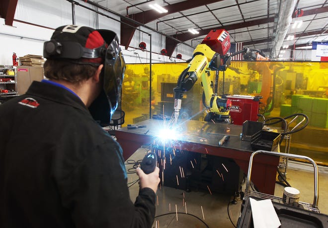 Welder Austin Croft uses the Kaisu robotic arm to weld together two pieces of metal during a demonstration at the Sisu grand reopening Friday. [PHOTO BY MIKE PARKER]