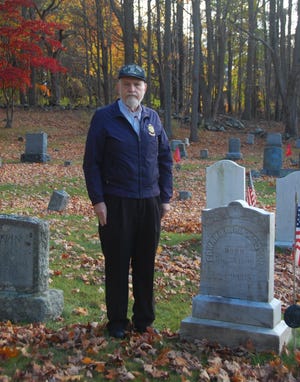 Former Rogers-Ramsdell American Legion Post Commander Donald Hands stands by the First Parish Cemetery gravestone of Edward E. Ramsdell, killed in 1918, Argonne, France.