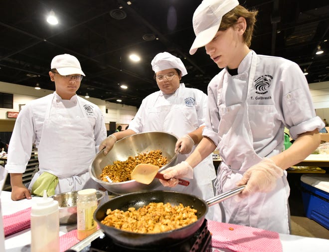 Frank H. Peterson culinary students Jae Moon (from left), 16, Peter Gil, 17, and Trevor Galbreath, 17, prepare their recipe titled "Bombastic Taco Flatbread" for children to try during the sixth annual Food Show on the Prime Osborn Convention Center in Jacksonville. [Will Dickey/Florida Times-Union]