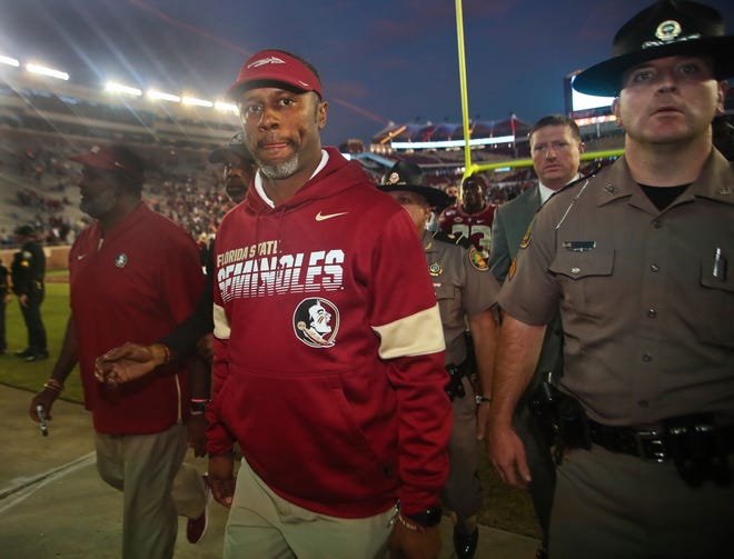 Florida State head coach Willie Taggart leaves after a game against Miami Saturday in Tallahassee. Florida State lost 27-10, and fired head coach Taggart on Sunday. Defensive line coach Odell Haggins, back left, has been named interim head coach. [Phil Sears/The Associated Press]