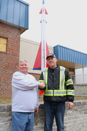 Bill Hoover, commander of Joe Stickell American Legion Post 15 in Waynesboro, and Tom Shockey shake hands in front of the restored missile that was returned to Legion headquarters Thursday afternoon. Tom Shockey Collision restored the missile in support of the club. JOHN IRWIN/THE RECORD HERALD