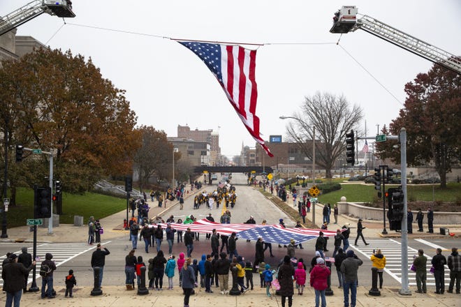 In this file photo, a large flag presented by the Springfield Elks Lodge 158 turns the corner at Second Street and Capitol Avenue, passing under another flag hoisted by the Village of Sherman and Springfield fire departments during the Veterans Day parade in 2018. [The State Journal-Register file photo]
