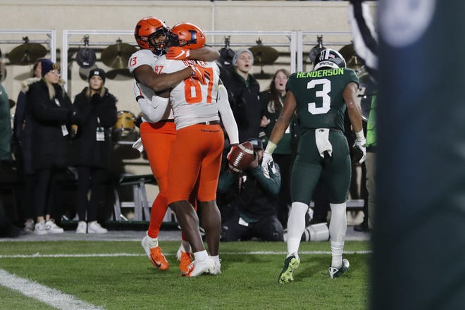 Illinois wide receiver Caleb Reams (13) hugs teammate tight end Daniel Barker (87) after Baker scored in the closing seconds to defeat Michigan State during the second half of an NCAA college football game, Saturday, Nov. 9, 2019, in East Lansing, Mich. (AP Photo/Carlos Osorio)