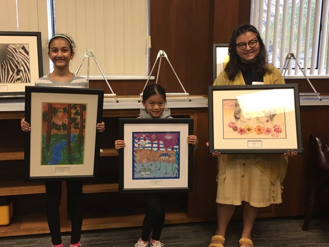 Honored Pennsbury School District students, from left, Naisha Kabadi, Sarah Huynh and Alexis Kamat hold up their works of art recently admitted into the district’s permanent collection at the administration building in Falls. [COURTESY PENNSBURY SCHOOL DISTRICT]