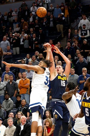 Denver Nuggets' Nikola Jokic, right, of Serbia, shoots the go-ahead basket over Minnesota Timberwolves' Karl-Anthony Towns in the final seconds in overtime Sunday in Minneapolis. The Nuggets won 100-98. [JIM MONE/THE ASSOCIATED PRESS]