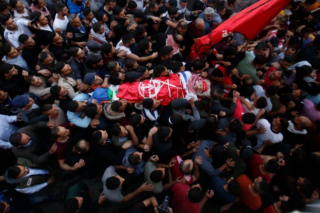 Palestinian mourners carry the body of Omar Badawi, 22, during his funeral at the al-Arroub refugee camp in the West Bank city of Hebron on Monday. Badawi was shot in the chest during the confrontation with Israeli forces in the Aroub refugee camp near the city of Hebron on Monday afternoon. It gave no further details. [MAJDI MOHAMMED/THE ASSOCIATED PRESS]