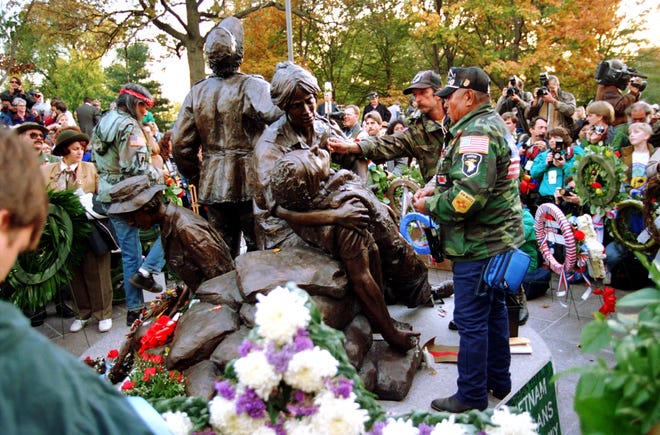 Vietnam veterans place mementos on the Vietnam Women's Memorial during the dedication ceremony of the bronze sculpture depicting three nurses and a wounded soldier, by Glenna Goodacre, in Washington, D.C., Thursday, Nov. 11, 1993. Thousands of veterans attended the dedication of the memorial, which honors more than 11,000 women who served in the Vietnam War. (AP Photo/Marcy Nighswander)