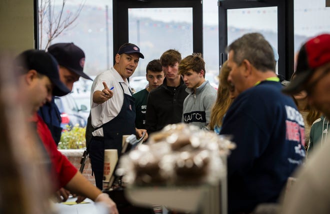 John Helm, Jersey Mike's Subs franchisee, let, helps some customers as they wait in liine at the new sandwhich shop in Sparta's North Village Complex last week during the sub shop’s grand opening in Sparta. [Photo by Daniel Freel/New Jersey Herald (NJH)]