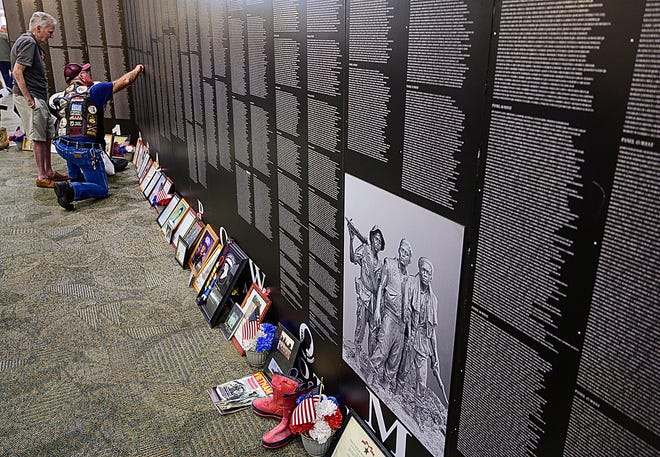 Men look for names on the Vietnam Traveling Memorial Wall in the lobby of the Anastasia Baptist Church in St. Augustine on Monday, November 11, 2019 before the start of the county’s Veterans Day celebration. The traveling memorial, which is a smaller scale replica of the Vietnam Memorial in Washington D.C., lists the 58,220 names of U.S. Vietnam War deaths. [PETER WILLOTT/THE RECORD]