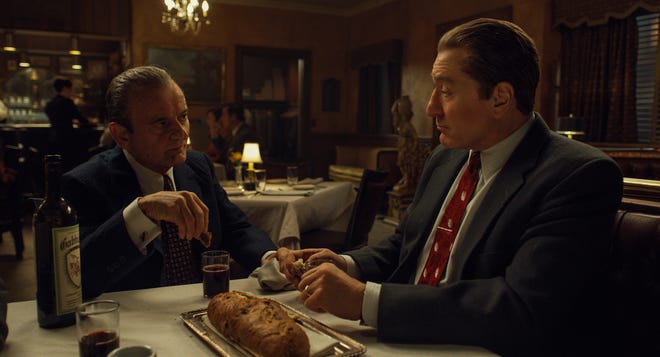 Dipping bread in wine, known as Intinction, speaks to the shared Catholic traditions of Russell Bufalino (Joe Pesci) and Frank Sheeran (Robert De Niro). [Netlfix]