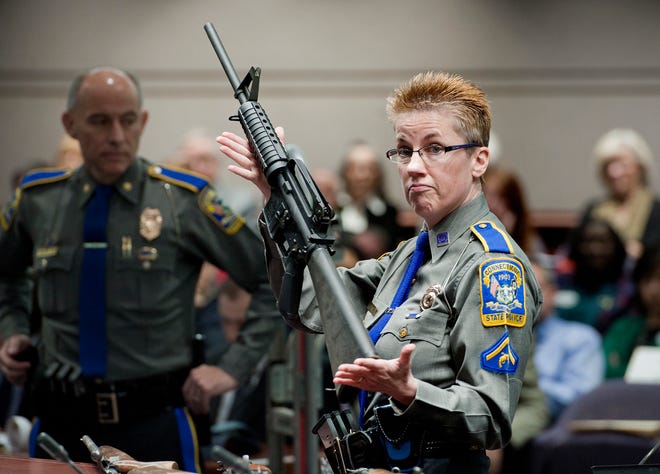 Firearms training unit Detective Barbara J. Mattson, of the Connecticut State Police, holds up a Bushmaster AR-15 rifle, the same make and model of gun used by Adam Lanza in the Sandy Hook School shooting, for a demonstration in January 2013 during a hearing of a legislative subcommittee reviewing gun laws, at the Legislative Office Building in Hartford, Conn. The Supreme Court said Tuesday a survivor and relatives of victims of the Sandy Hook Elementary School shooting can pursue their lawsuit against the maker of the rifle used to kill 26 people. [JESSICA HILL/THE ASSOCIATED PRESS (FILE)]