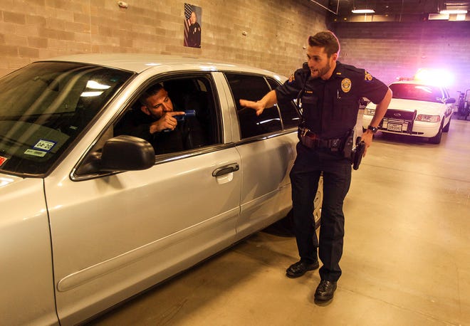 Police Det. Mike McCabe, in the car, and Lt. Tom Sloan demonstrate a traffic stop scenario where an officer is held at gunpoint during the Round Rock Citizens Police Academy on Tuesday. [PHOTO BY ARIANA GARCIA]