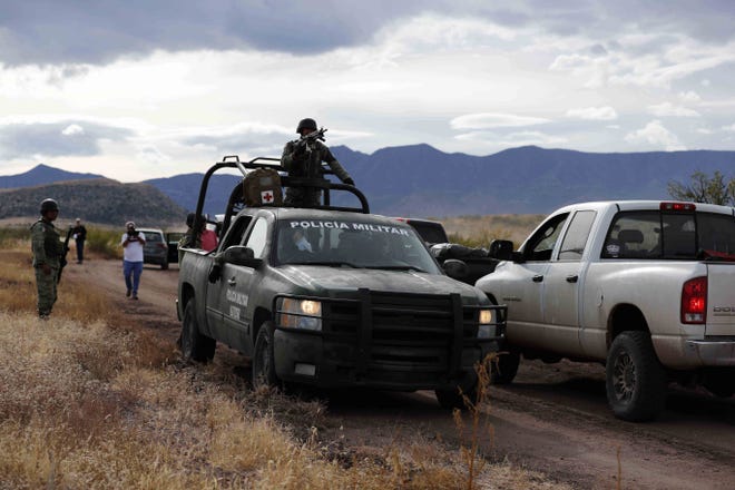 Mexican national guard troops protect a road Nov. 6 as a caravan of friends of the LeBaron family travels to La Mora, Sonora state, Mexico. Drug cartel gunmen ambushed three SUVs along a dirt road, slaughtering six children and three women of the extended LeBaron family, all U.S. citizens living in northern Mexico. [AP PHOTO/MARCO UGARTE]