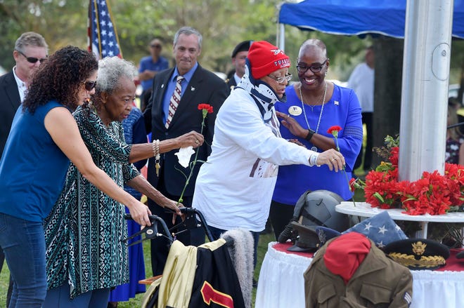 The family of Chief Master Sgt. Walt Richardson place carnations at the flag base during Monday’s Veterans Day Celebration at Beal Memorial Cemetery in Fort Walton Beach. Richardson, who passed away in 2014, referred to himself as a “second generation” Tuskegee Airmen and was one of 1,500 African American enlisted airmen chosen to be moved to previously all-white units when the U.S. military began to integrate in the late 1940s. [DEVON RAVINE/DAILY NEWS]