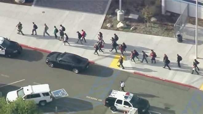 People are lead out of Saugus High School after reports of a shooting on Thursday, Nov. 14, 2019 in Santa Clarita, Calif. The Los Angeles County Sheriff’s Department says on Twitter that deputies are responding to the high school about 30 miles (48 kilometers) northwest of downtown Los Angeles. The sheriff’s office says a male suspect in black clothing was seen at the school. (KTTV-TV via AP)