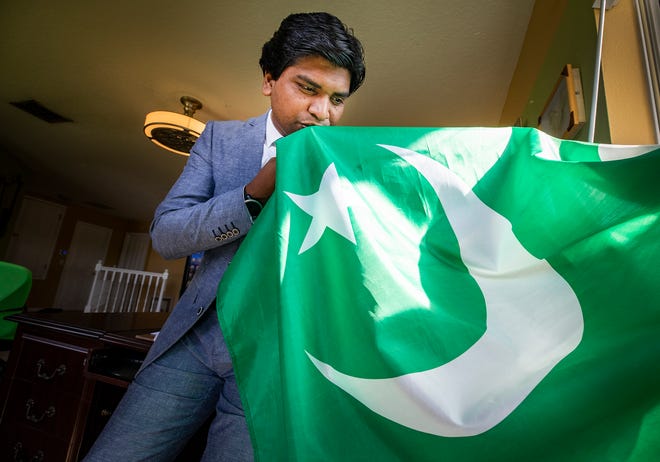 Junaid Saqib kisses the flag of his native country Pakistan at his home in Lakeland. Junaid is a Christian from Pakistan, who fled to the United States in 2017 because of religious persecution. He remains actively involved with the Pakistan Minority Rights Commission
. [ERNST PETERS/THE LEDGER]