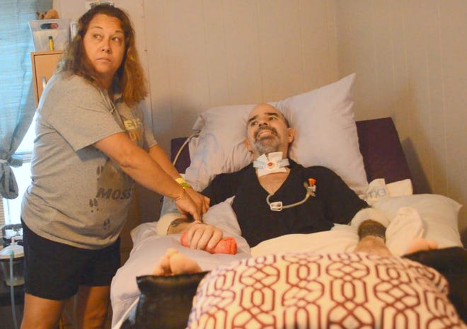 Lisa Tatro, left, adjusts a bandage on her husband Joel, right, who was shot and paralyzed in February. A community fundraiser is underway to help the Tatros purchase a wheelchair that could help Joel Tatro gain some independence. [News-Journal/Casmira Harrison]