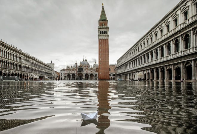 A paper boat floats in a flooded St. Mark's Square in Venice, Friday, Nov. 15, 2019. Exceptionally high tidal waters, peaking at 1.54 meters (5 feet) above sea level, returned to Venice on Friday, prompting the mayor to close the iconic St. Mark's Square and call for donations to repair the Italian lagoon city just three days after it experienced its worst flooding in 50 years. (AP Photo/Luca Bruno)