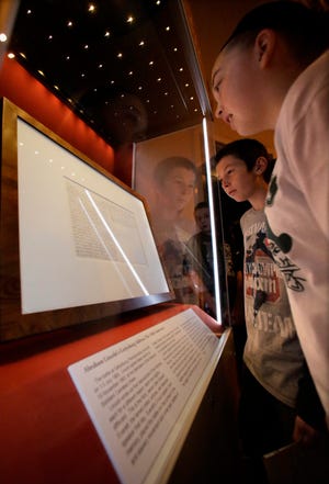 In this Friday, Nov. 15, 2013 photo, school groups and visitors view Illinois' copy of the Gettysburg Address at the Abraham Lincoln Presidential Museum and Library. It is on display again through early December. [AP File Photo/Seth Perlman]
