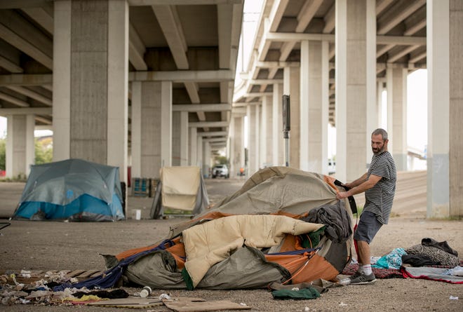 Danny Bonura moves his tent as state workers prepare to clean a homeless camp in South Austin this month. [JAY JANNER/AMERICAN-STATESMAN]