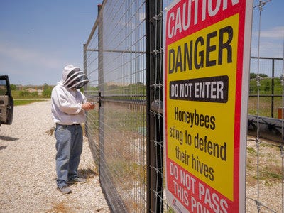 Texas Beekeeper, Charlie Agar, passes a warning sign before checking his Africanized beehives.