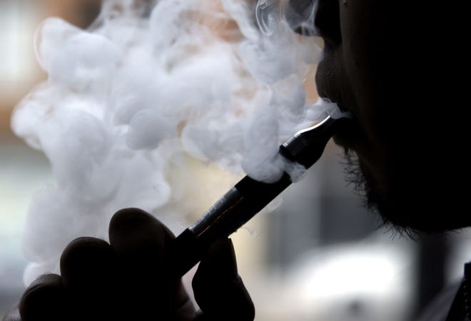 A man vapes in Florida in a file photo. President Donald Trump has pulled back from plans to ban e-cigarette flavors. [AP FILE PHOTO]