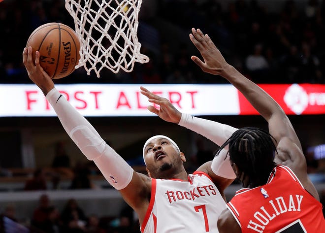 FILE - In this Nov. 3, 2018, file photo, Houston Rockets forward Carmelo Anthony, left, drives to the basket against Chicago Bulls forward Justin Holiday during the first half of an NBA basketball game in Chicago. Anthony is returning to the NBA with the Portland Trail Blazers. The 10-time All-Star has not played since a short stint with the Rockets ended a little more than a year ago after just 10 games. (AP Photo/Nam Y. Huh, File)