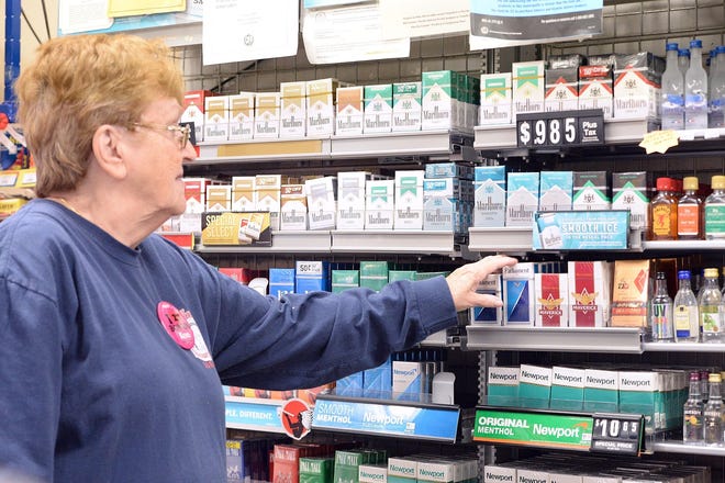 Jean Doherty straightens out a pack of cigarettes at Bob's Famous Foodmart and Discount Liquors in Stoughton on Thursday, Oct. 31, 2019. (Marc Vasconcellos/The Enterprise)