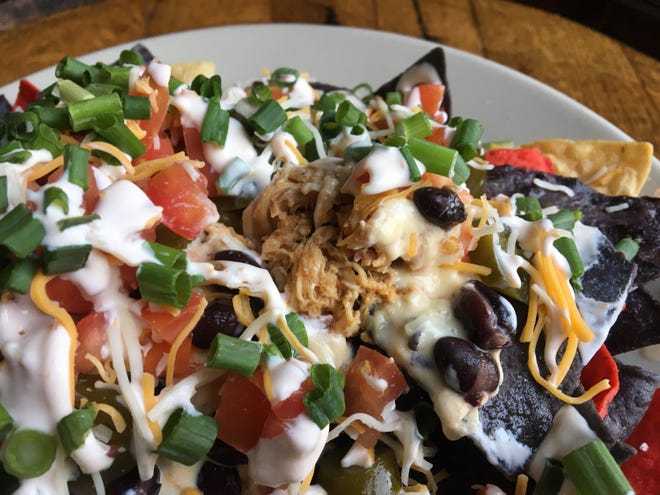 Front Street Brewery’s famous pulled chicken nachos are made with slow-cooked and hand-pulled chicken, queso, black beans, jalapenos, tomatoes and shredded cheese, among other toppings. [ASHLEY MORRIS/STARNEWS]