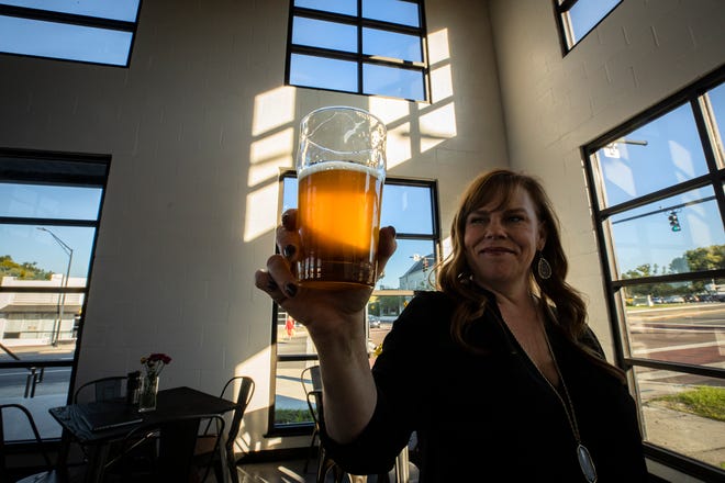 Jenn Batts, co-owner of The Yard on Mass, with a Grove Roots beer at the beer garden and food truck venue which opens Friday in downtown Lakeland. [ERNST PETERS/THE LEDGER]