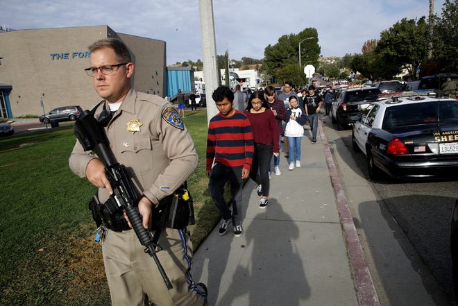 FILE - This Nov. 14, 2019 file photo shows a California Highway Patrol officer escorting students out of Saugus High School after a shooting on the campus in Santa Clarita, Calif. Authorities say the teenager who shot five classmates, killing two, at a Southern California high school used an unregistered "ghost gun." Los Angeles County Sheriff Alex Villanueva Villanueva told media outlets Thursday, Nov. 21, 2019 that Nathaniel Tennosuke Berhow's semi-automatic handgun had been assembled and did not have a serial number. Authorities are still working to determine how Berhow got the handgun. Berhow died from a self-inflicted gunshot wound after the shooting. (AP Photo/Marcio Jose Sanchez, File)