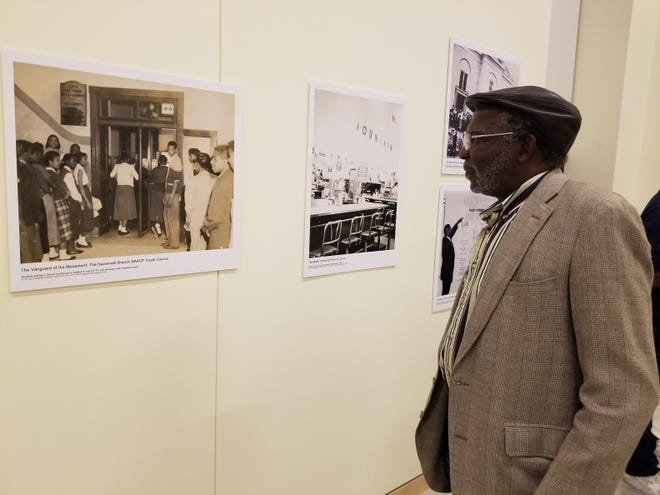 Herman West looks at a photograph of students waiting in line to register to vote during the opening reception Thursday night. [Eric Curl/For the Savannah Morning News]