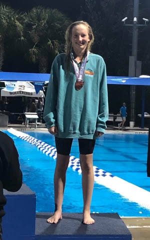 Mosley swimmer Lily Bradford stands on the podium after finishing third in the Girls 100 Yard Backstroke at last week’s 3A swimming and diving championships in Stuart. [MOSLEY PHOTO]