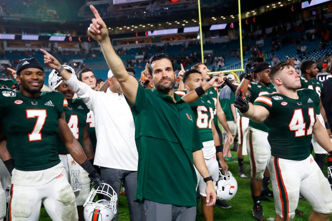 Miami head coach Manny Diaz, center, celebrates with players after Miami defeated Louisville 52-27 Nov. 9 in Miami Gardens. [ WILFREDO LEE/THE ASSOCIATED PRESS ]