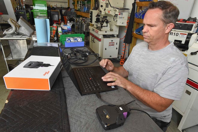 Chris McCollum, chief operating officer of RaceChip Americas Inc. connects one of the company’s performance tuning boxes (foreground) to a computer Friday at Emerald Coast Motorsports in Fort Walton Beach. The company recently moved its U.S. headquarters from Orange County, California to Fort Walton Beach. [DEVON RAVINE/DAILY NEWS]