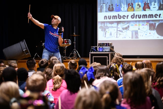 Troy Kryzalka, the Number Drummer, shows students how to drum on their cowbell during his performance Friday at Eastover-Central Elementary School. [Andrew Craft/The Fayetteville Observer]